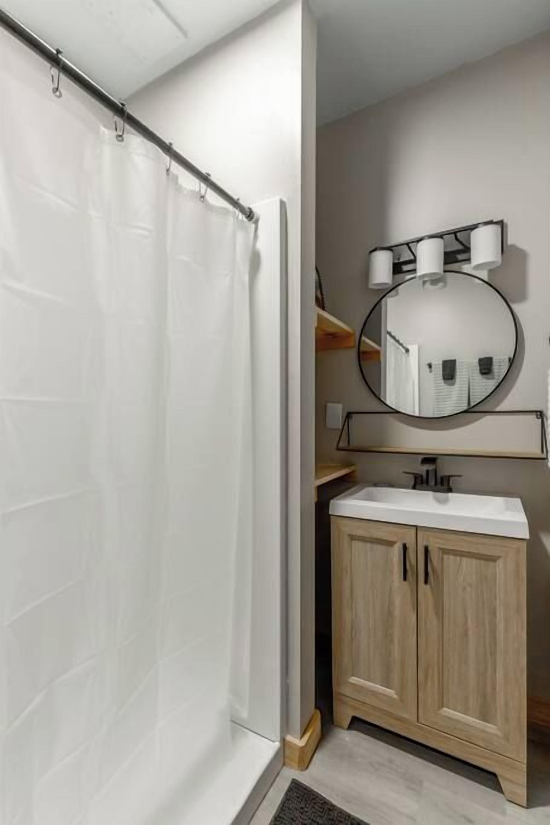 A bathroom with a shower, a sink, and a mirror.