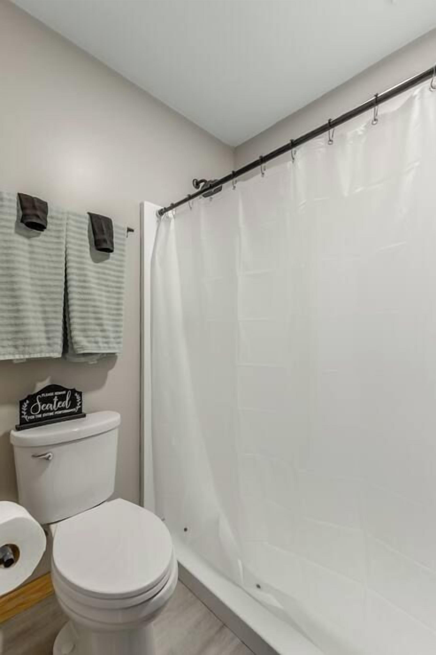 Un baño con inodoro, cortina de ducha y toallero con toallas.