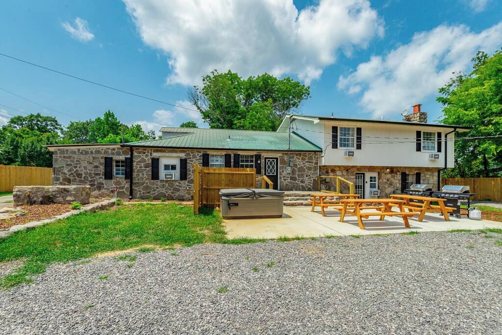 A two-story stone building with a green roof, outdoor seating area, and a grill.