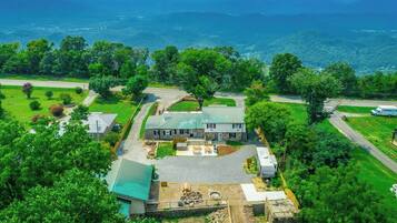 A large house with a spacious yard, a driveway, and a view of the surrounding landscape.