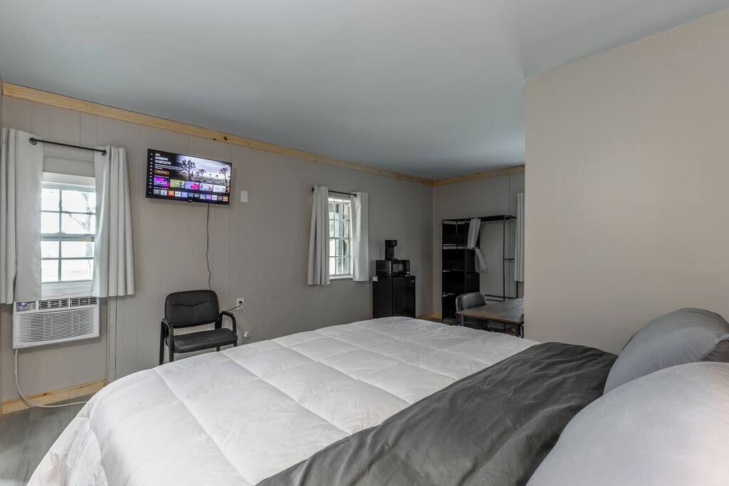 A hotel room with a large bed, a TV mounted on the wall, a desk, and a wardrobe.