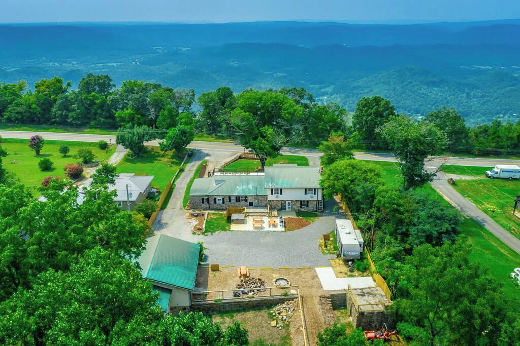 Ein großes Haus mit einem weitläufigen Garten, einer Auffahrt und Blick auf die umliegende Landschaft.