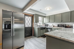 Eine moderne Küche mit einem Edelstahl-Kühlschrank, einem Einbauofen und einer Mikrowelle.