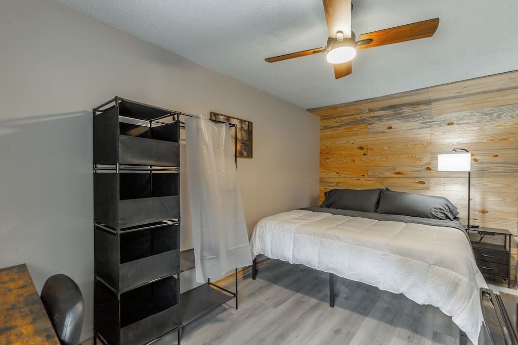 Un dormitorio con cama, ventilador de techo, armario y mesita de noche.