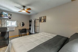 A hotel room with a bed, a desk, a chair, a ceiling fan, a TV, and a window. - Wildflower Hotel on Lookout Mountain 2 (Rising Fawn)