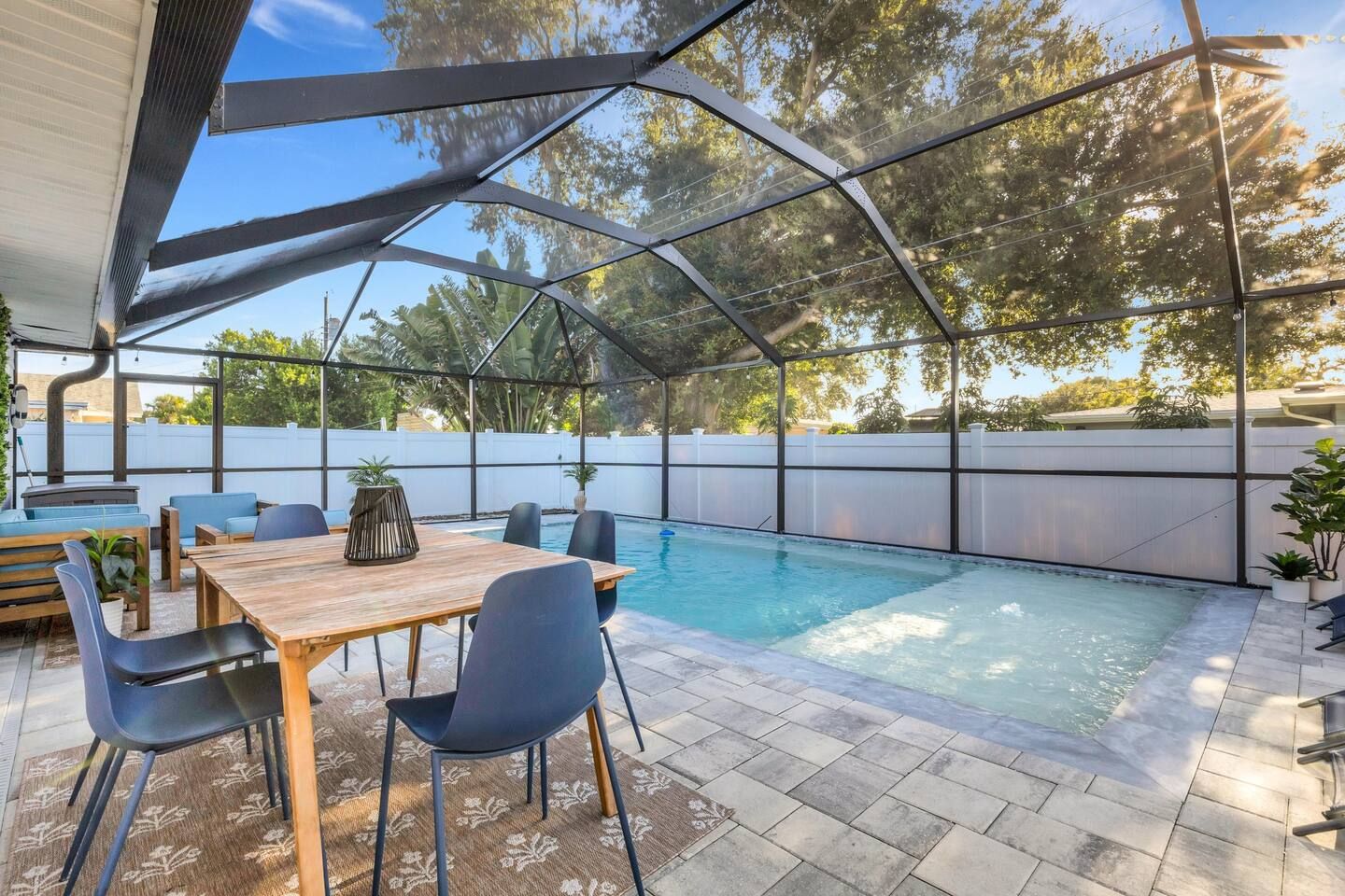 A covered outdoor area with a pool, seating, and a grill.