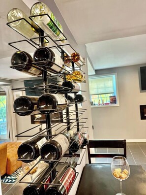 A wine rack with multiple bottles and a glass of wine on a table.