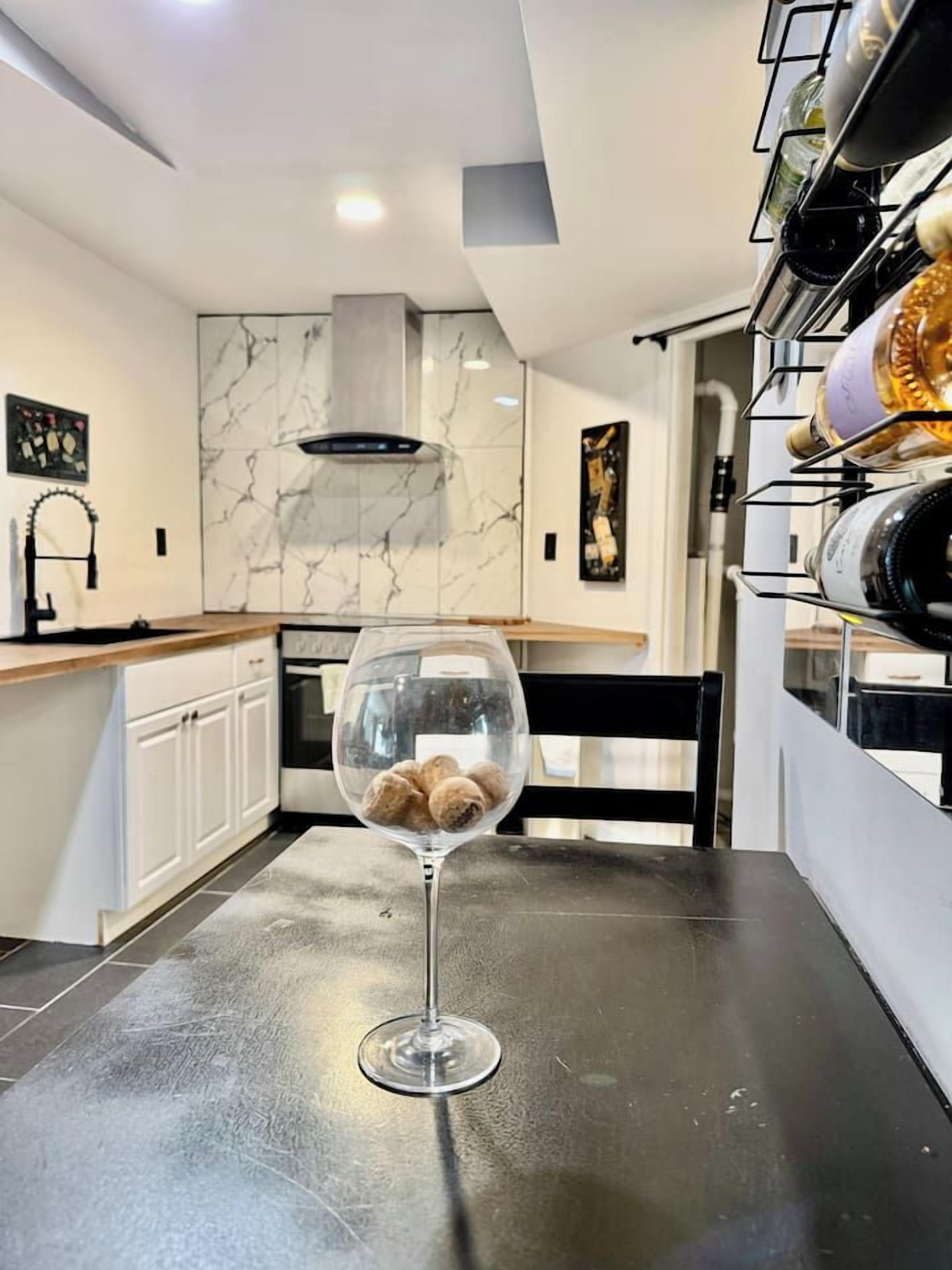 A kitchen with a marble backsplash, a wine glass with a bottle, and a wine rack.