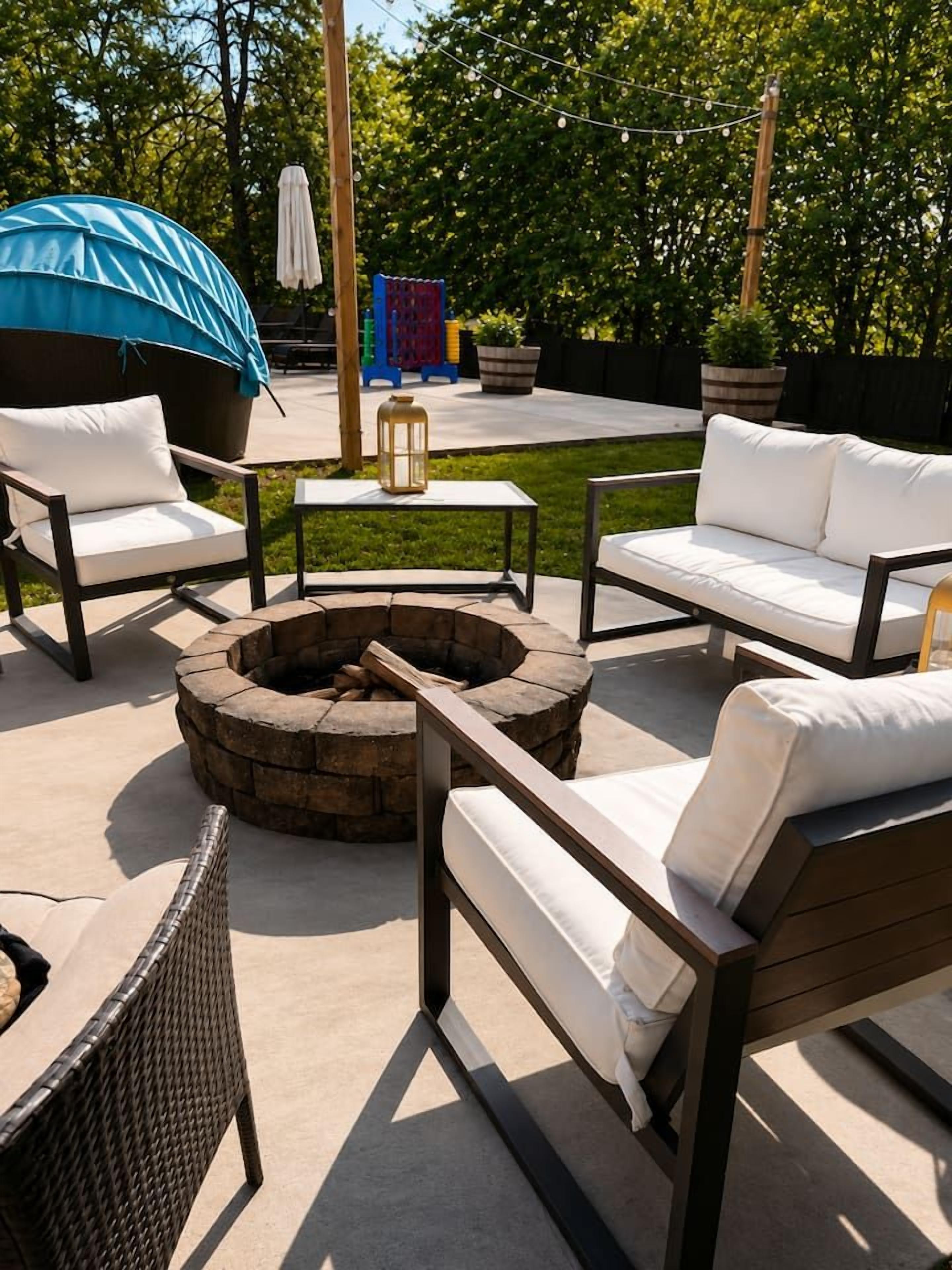 An outdoor patio area with a fire pit, seating, and a covered table.