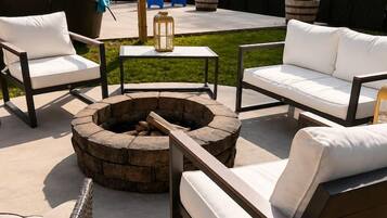 An outdoor patio area with a fire pit, seating, and a covered table.