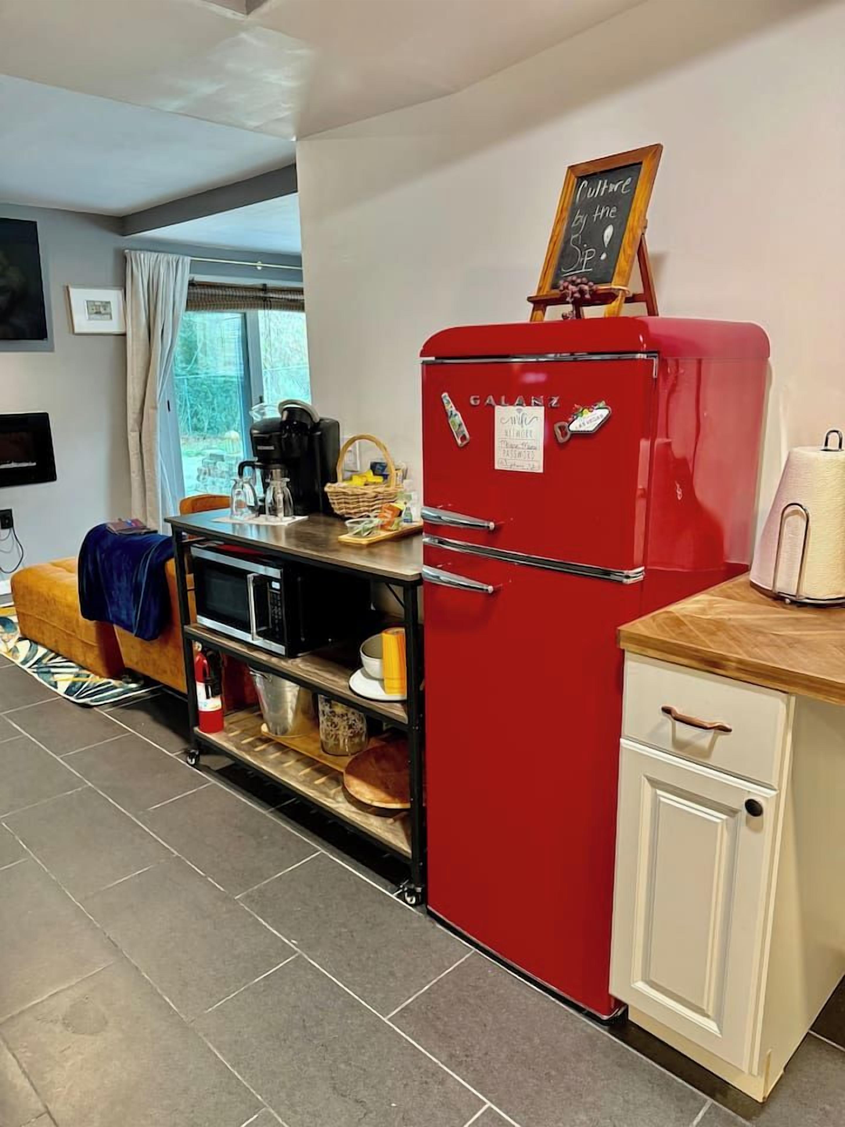 A compact kitchen with a red refrigerator, a microwave, and a small cabinet.