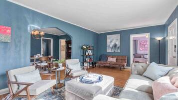 A living room with a blue wall, a sofa, a coffee table, and a dining area with chairs and a table.