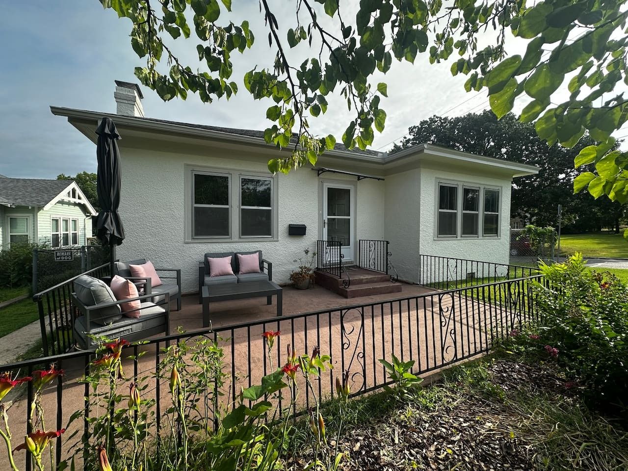 A house with a patio, a covered seating area, and a fenced yard.