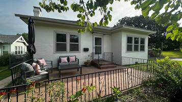 A house with a patio, a covered seating area, and a fenced yard.