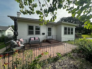 A house with a patio, a covered seating area, and a fenced yard.