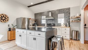 A modern kitchen with a central island, stainless steel appliances, and a brick backsplash.