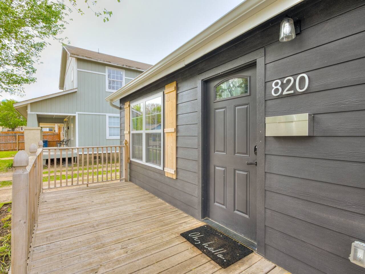 A residential building with a dark grey exterior, a wooden deck, and a mailbox with the number 820.