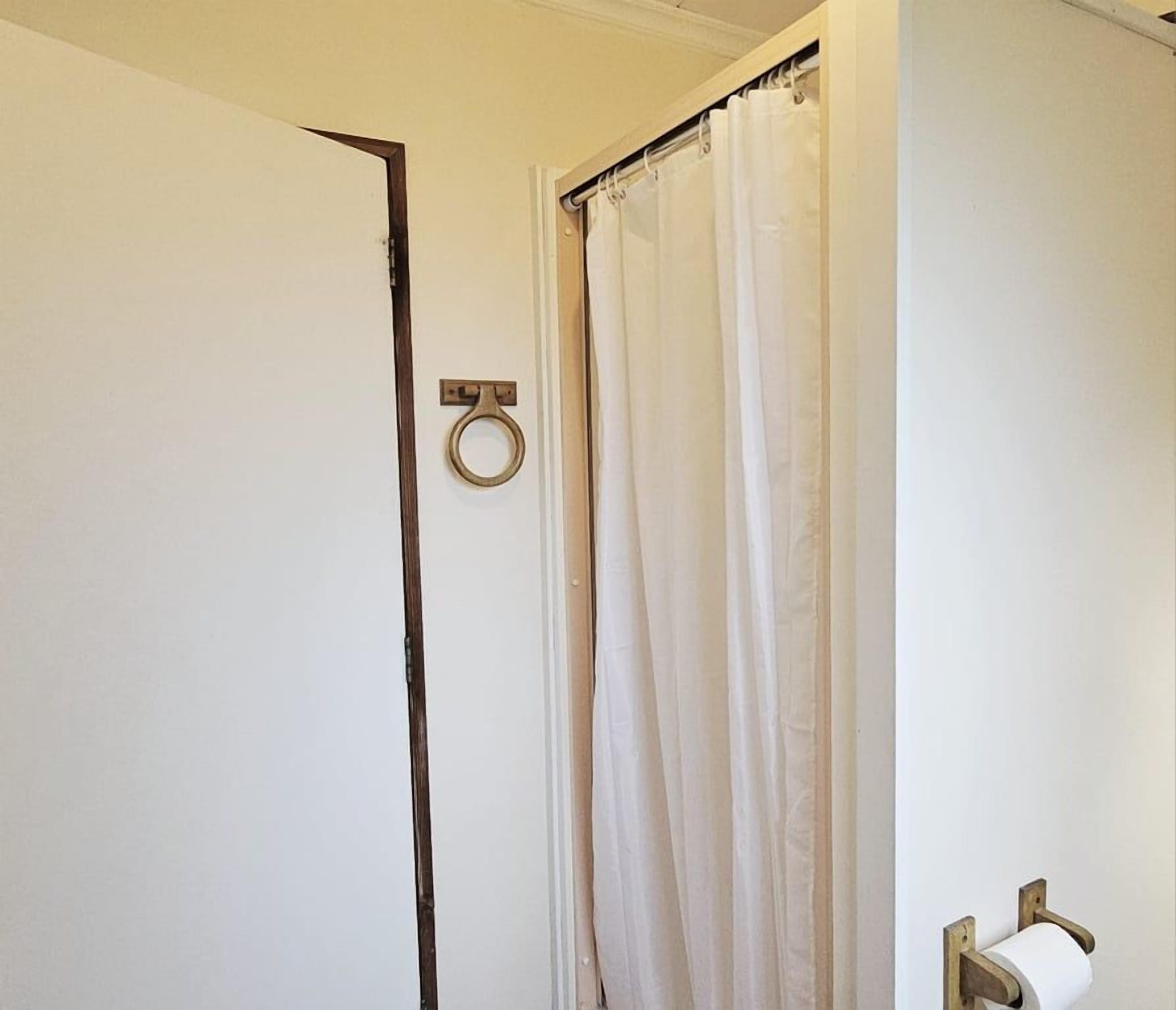 Une salle de bain équipée de toilettes, d’un porte-serviettes et d’un rideau de douche.