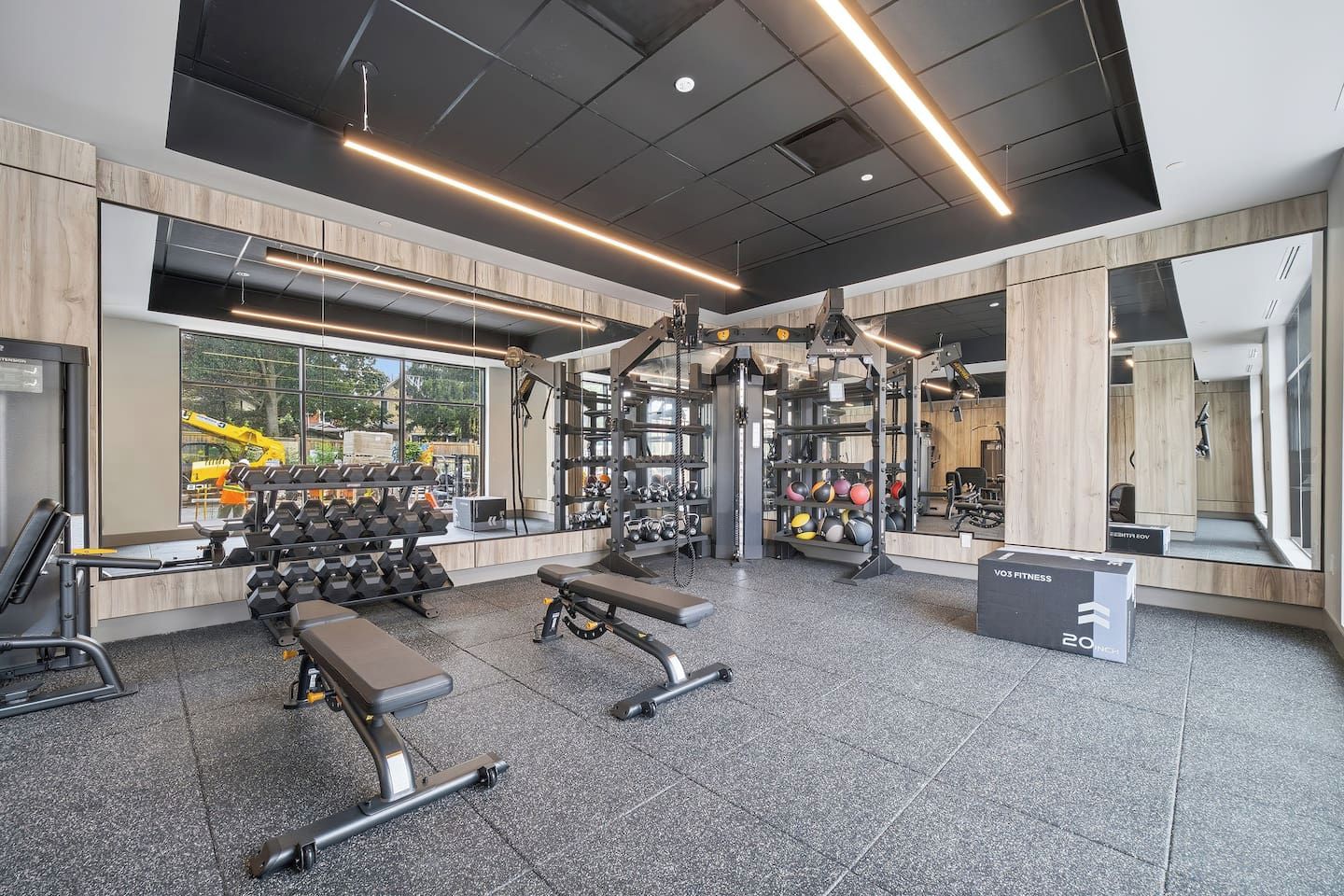 A modern gym with weightlifting equipment, benches, and a variety of exercise balls.