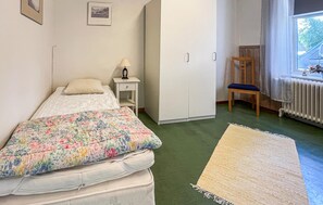 A bedroom with a bed, a nightstand, a chair, a wardrobe, and a window with curtains. - 7 bedroom stunning home in östra ljungby (Östra Ljungby)