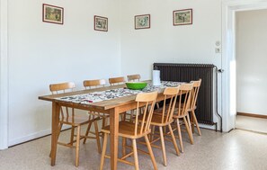 A dining area with a wooden table and chairs, a green bowl, and a radiator. - 7 bedroom stunning home in östra ljungby (Östra Ljungby)