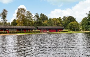A lakeside building with a red facade, surrounded by trees and a calm water body. - 4 bedroom gorgeous home in örkelljunga (Örkelljunga)