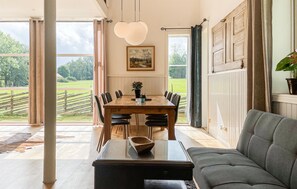 Ein Essbereich mit Holztisch und Stühlen, einer Couch und Blick ins Freie.