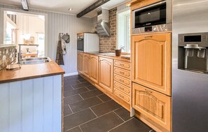 Eine Küche mit Holzausstattung, einem Edelstahlkühlschrank und einem Backofen von Bosch.