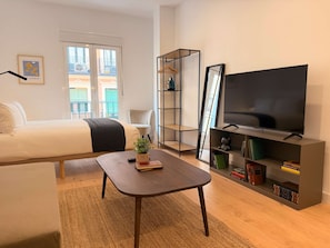 Ein modernes Wohnzimmer mit einem Bett, einem Couchtisch, einem Fernseher und einem Bücherregal.