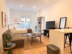 A modern living room with a sofa, a coffee table, a TV, and a bookshelf. - w* | Lovely 1BR w/ Balcony in Central Madrid (Madrid)