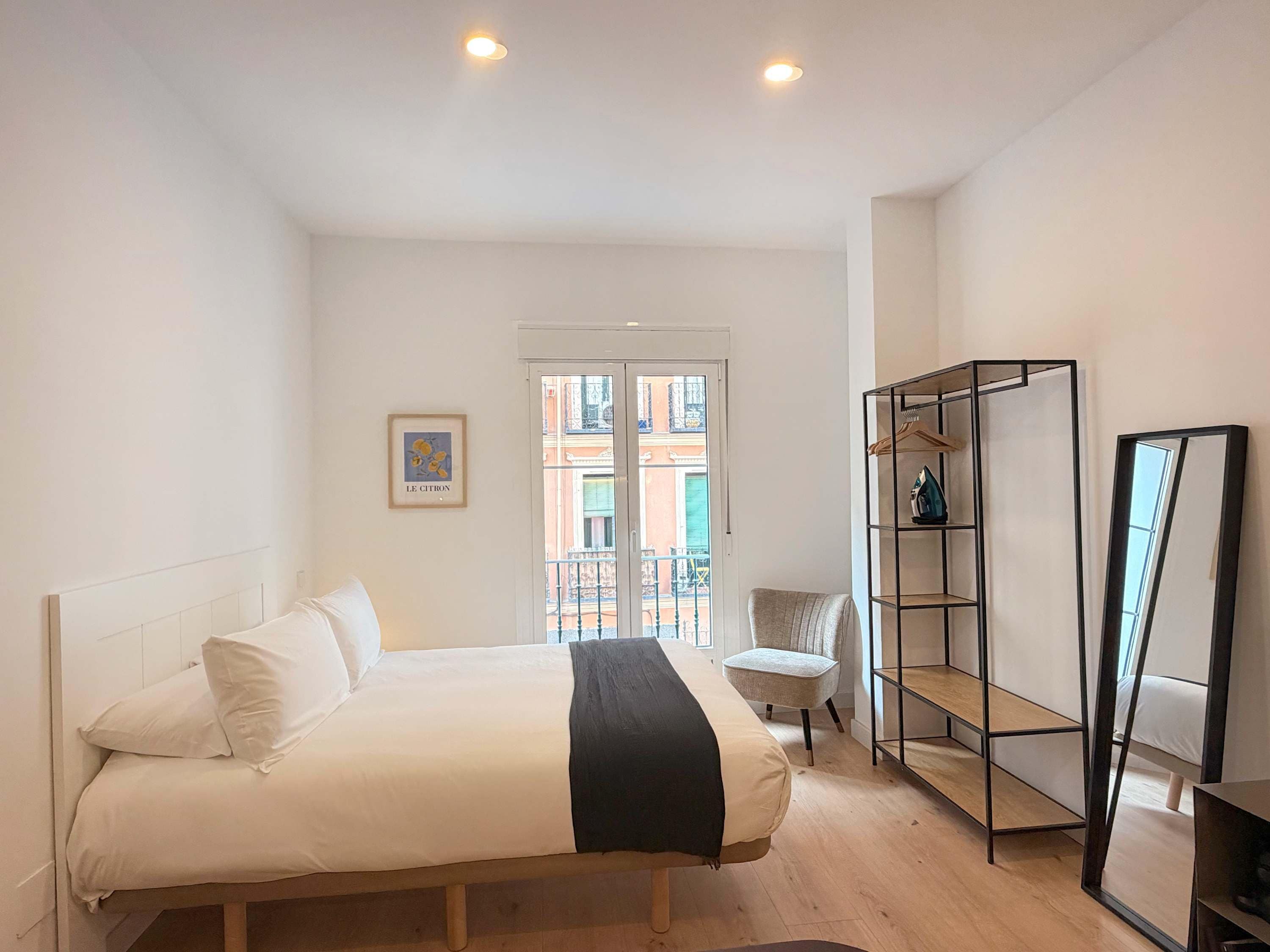 Ein Schlafzimmer mit einem Bett, einem Sessel, einem Kleiderschrank und einer Tür, die auf einen Balkon führt.
