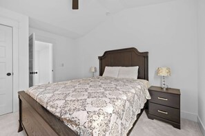 A bedroom with a bed, bedside tables, and a door. - Music City Home Base | Office + 98" TV | 30+ Days (Nashville)