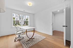 A modern, well-lit room with a white table, a white chair, and a patterned rug. - Music City Home Base | Office + 98" TV | 30+ Days (Nashville)