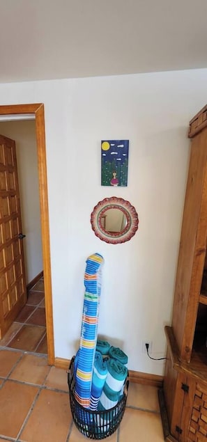 A room with a wooden door, a wall-mounted mirror, a framed picture, and a basket with rolled-up mats. - Casa Frida - Beach City retreat (Ensenada)