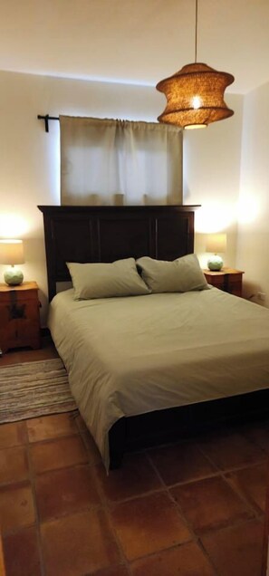 A bedroom with a bed, bedside tables, a hanging light fixture, and a window with curtains. - Casa Frida - Beach City retreat (Ensenada)