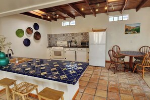 A kitchen with a tiled backsplash, a white refrigerator, and a dining area with wooden chairs. - Casa Frida - Beach City retreat (Ensenada)