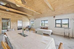 Ein Zimmer mit einem großen Tisch, zwei Betten und Blick ins Freie.