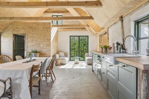 A modern kitchen with a large window, wooden beams, and a dining area with a table and chairs. - Charming holiday home on Northern Langeland (Tressebølle)