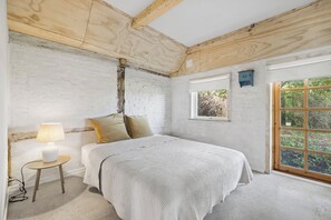A bedroom with a bed, a nightstand, a lamp, a window, and a view of greenery outside. - Charming holiday home on Northern Langeland (Tressebølle)