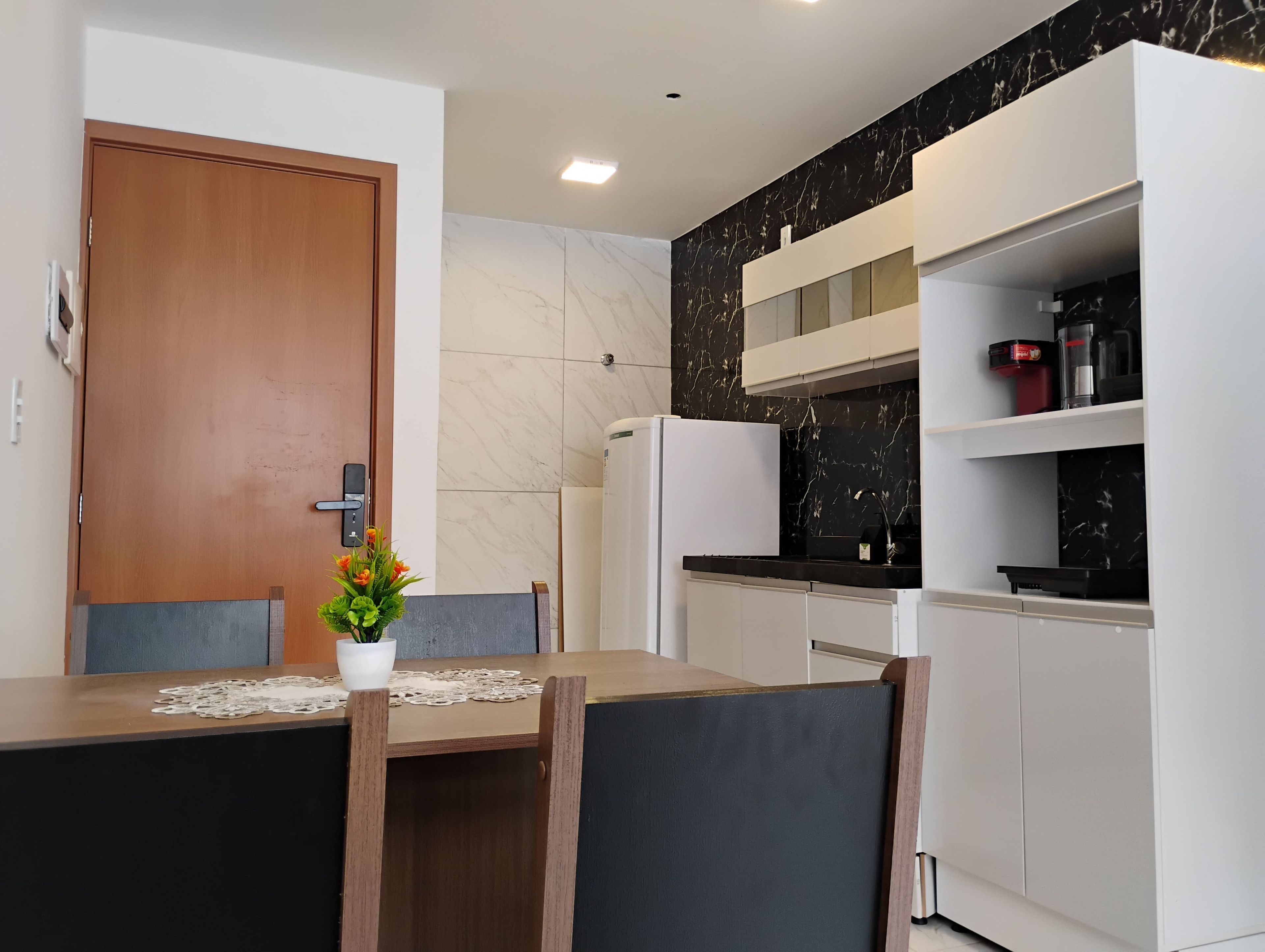 A modern kitchen with a marble backsplash, white cabinetry, and a built-in oven.