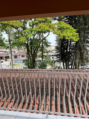 Ein Balkon mit einem Ziegeldach, mit Blick auf ein Wohngebiet mit Bäumen und Häusern.