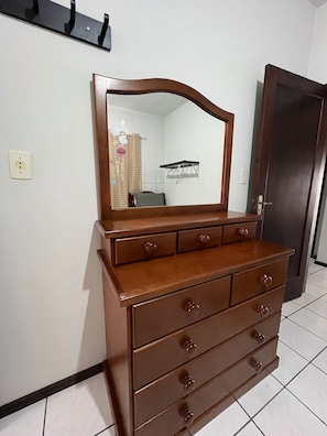 Uma cômoda de madeira com espelho, uma porta e uma prateleira fixada na parede.