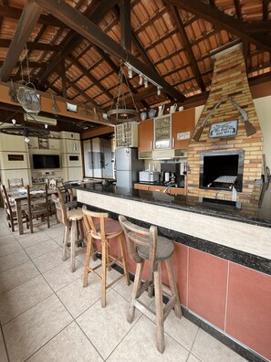 Uma cozinha com forno de tijolos, banquetas de madeira e piso de azulejos.