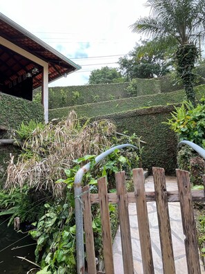 Ein Garten mit Holzzaun, Wasserspiel und Hecke.