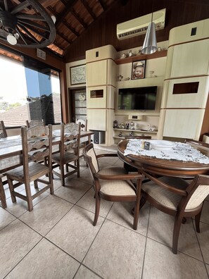 A dining area with a round table, wooden chairs, and a tiled floor. - House of the Master Brewer (Blumenau)
