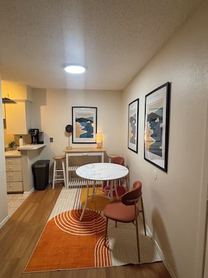 A compact kitchen with a dining area, including a table and chairs, a trash bin, and a coffee machine. -     Cozy 1BR Near Dallas Medical District  - Furnished + Utilities (Dallas)