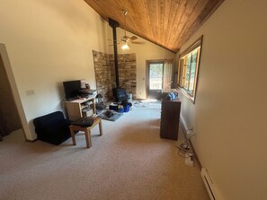 Ein gemütliches Wohnzimmer mit Kamin, Fernseher und einer Steinwand.