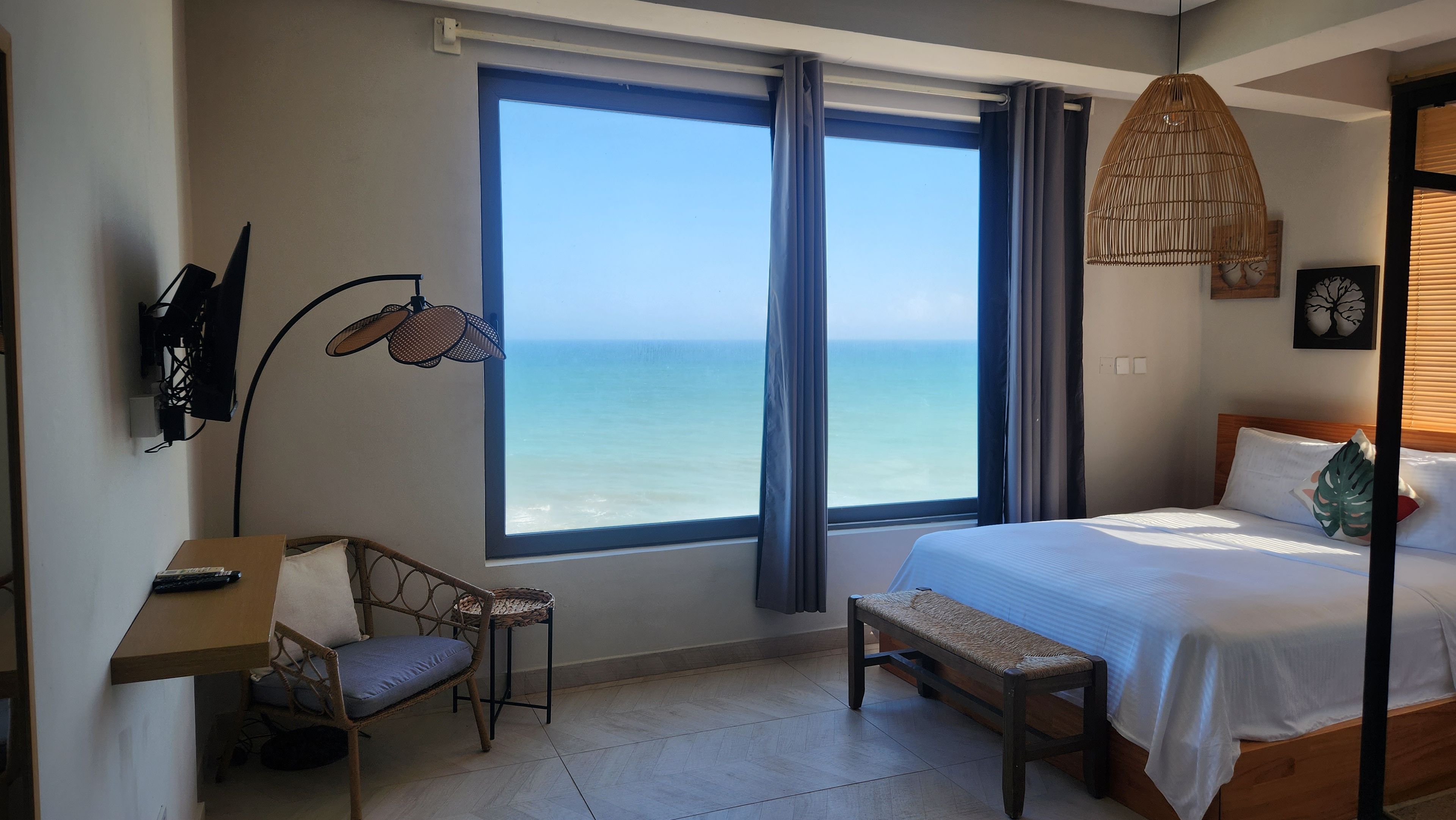 Un dormitorio con un ventanal grande, una cama, un escritorio y una silla.