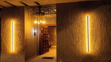 A hallway with textured walls and a wooden door, illuminated by vertical light strips.