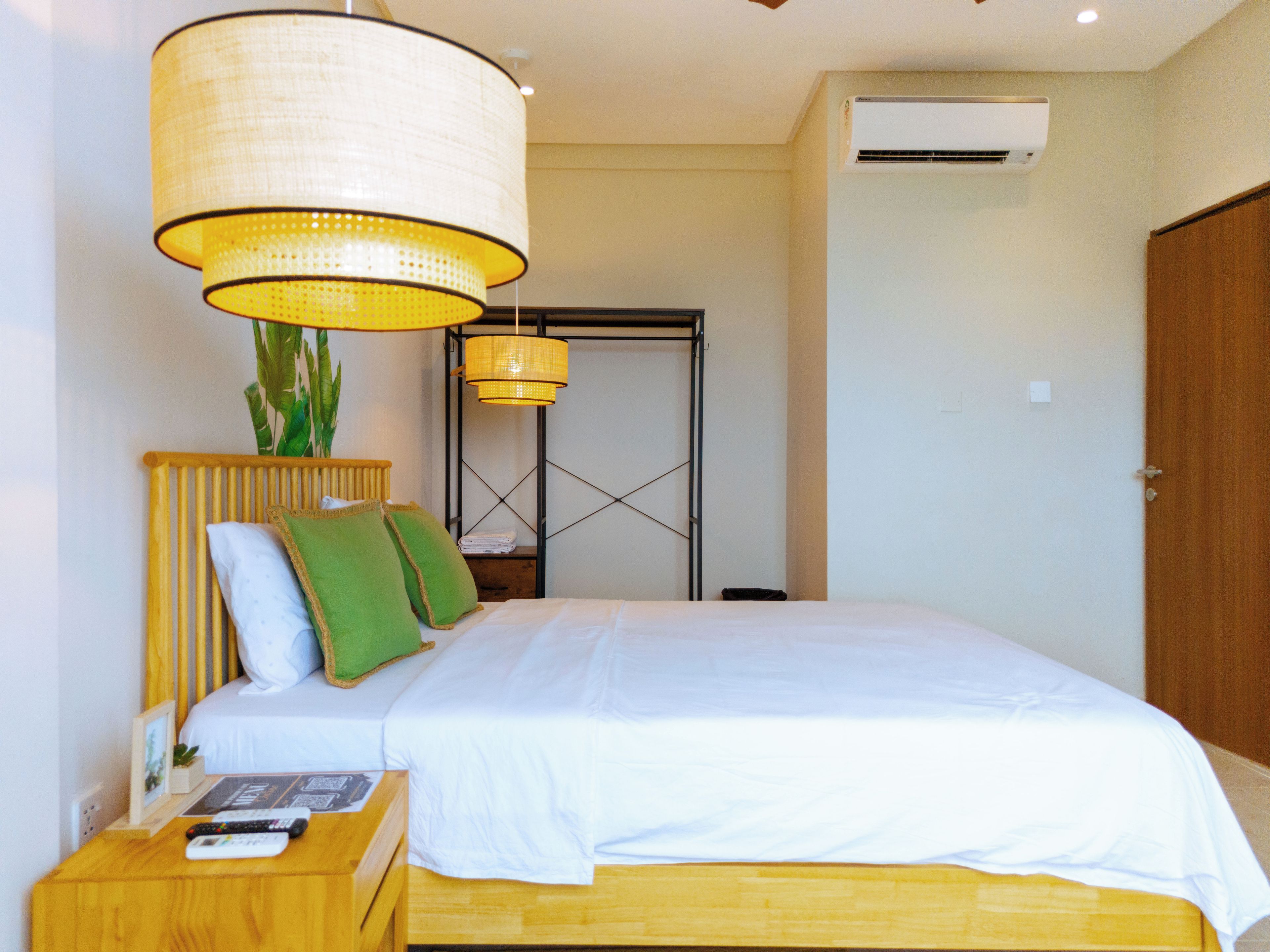 A neatly arranged hotel room with a bed, bedside table, and a hanging lamp.
